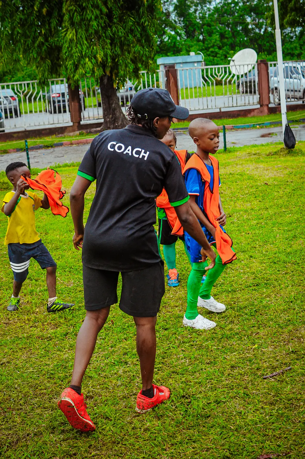 A coach gathering young players at the start of a session