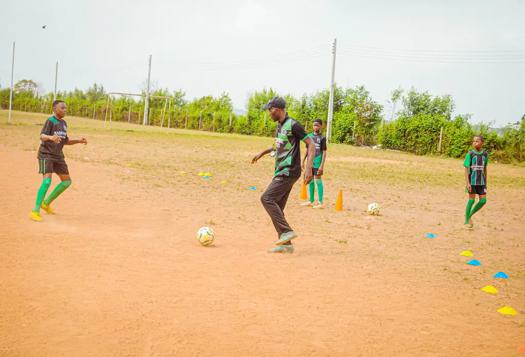 A wide view of young players training on a sand pitch